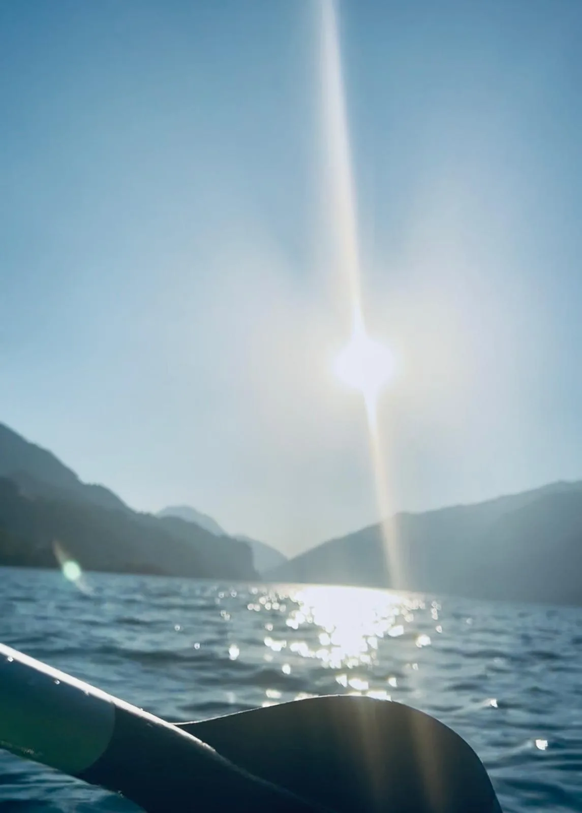 Paddelblatt im Vordergrund, dahinter glitzert die Sonne auf dem See